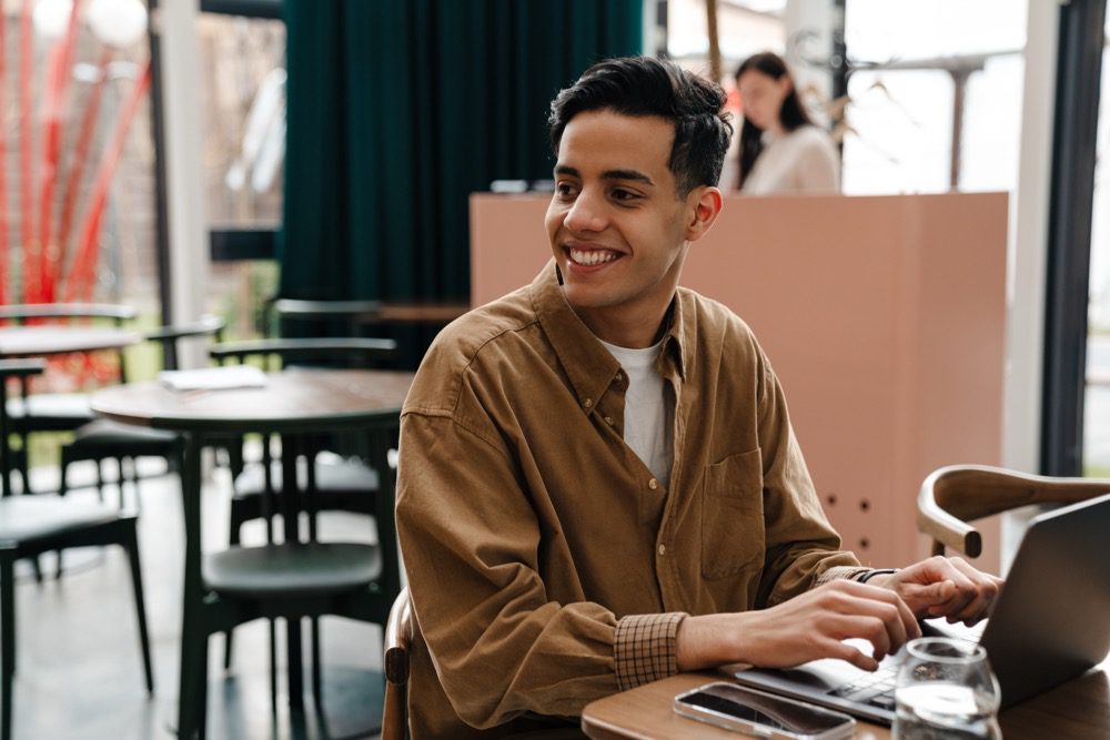 Young hispanic man student sitting at the cafe table indoors
