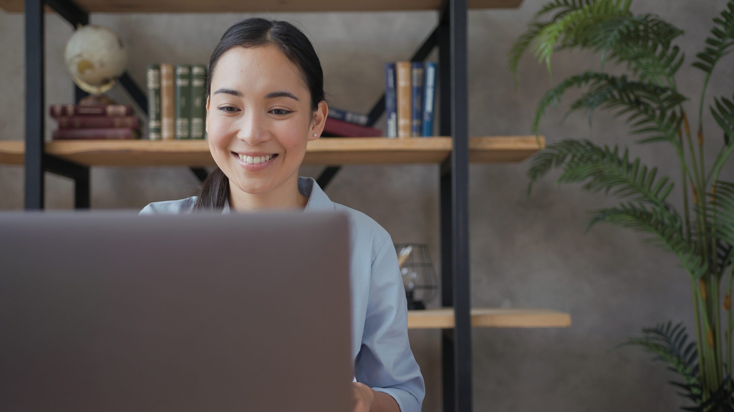 Close up portrait of smiling asian teacher conducts an online lesson using laptop