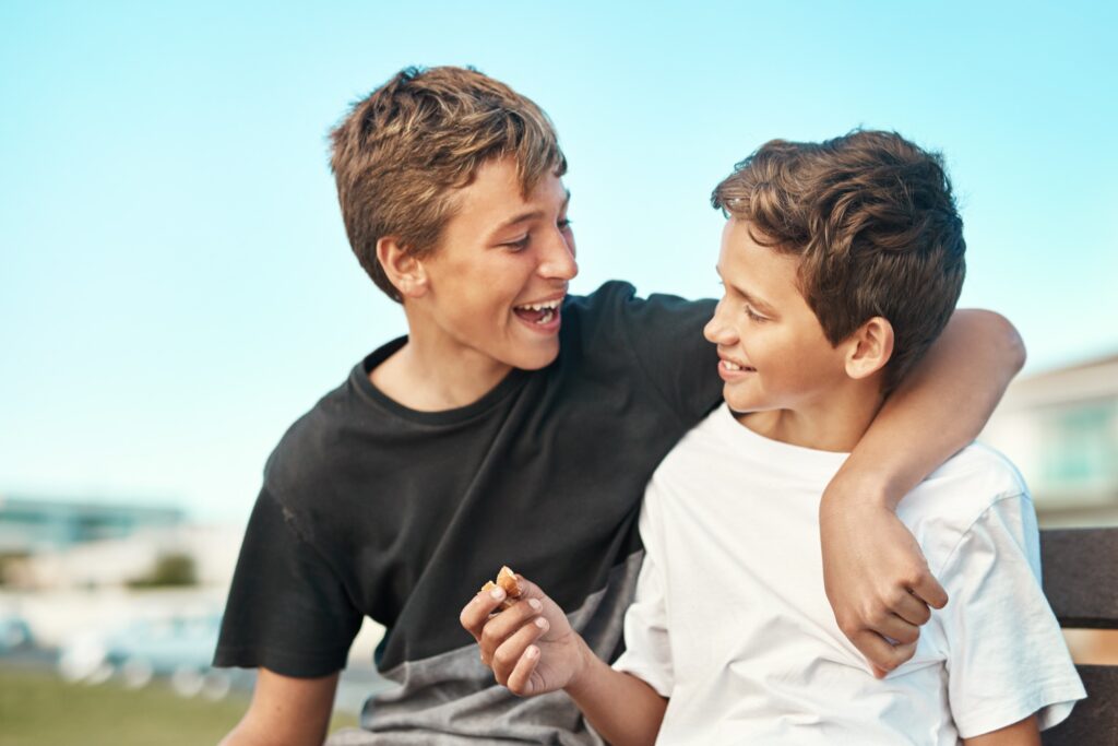 hot of two happy brothers sitting on a bench